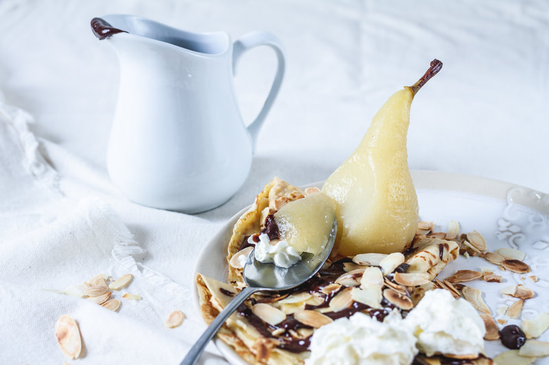 A delicious recipes of crepes (or pancakes) filled with vanilla pastry cream and topped with a poached pear and hot chocolate sauce